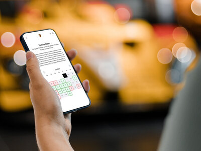 Eine Person hält ein Smartphone in der Hand, dass einen interaktiven Terminkalender zeigt