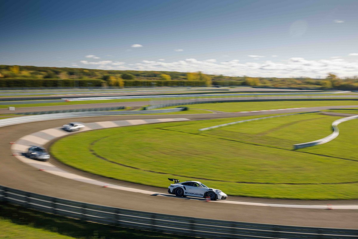 Mehrere Porsche 911 in der Gruppe fahren auf der Rundstrecke