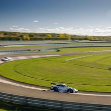 Mehrere Porsche 911 in der Gruppe fahren auf der Rundstrecke