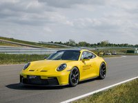 Ein gelber Porsche 911 GT3 wird auf der Rennstrecke des Porsche experience Center Leipzig mit der schwarz-weiß karierten Flagge abgewunken