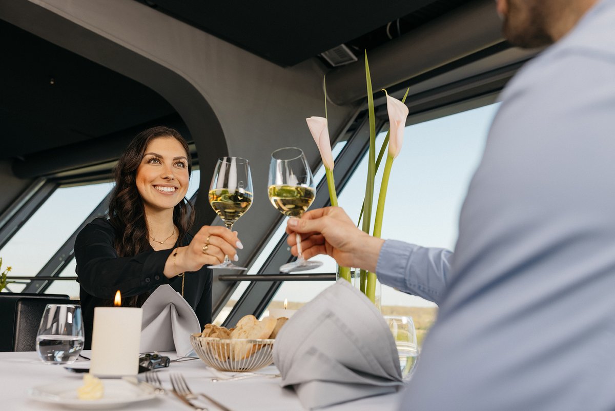 Frau prostet einem Mann mit einem Glas Weißwein zu