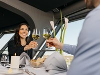 Eine junge Frau prostet ihrem Partner mit einem Glas Weißwein zu.