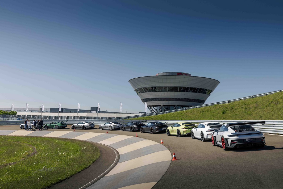 Mehrere Porsche 911 mit Teilnehmern auf der Rundstrecke während der Instrukteur ein Briefing gibt.