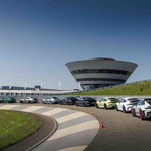 Mehrere Porsche 911 mit Teilnehmern auf der Rundstrecke während der Instrukteur ein Briefing gibt.