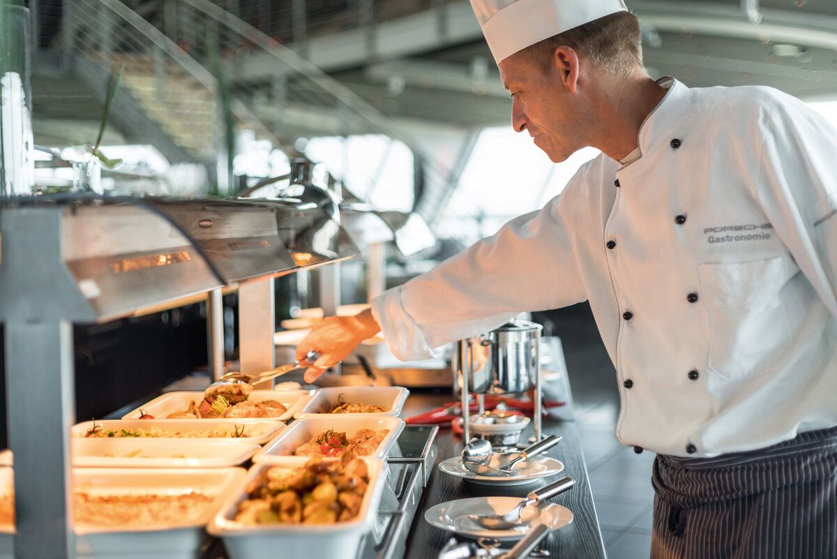 Snackbereich Warmes Buffet. Koch richtet Essen her.
