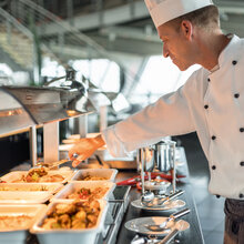 Snackbereich Warmes Buffet. Koch richtet Essen her.