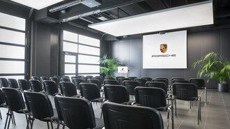 Große halle, Bestuhlung parlamentarisch. Leinwand und Rednerpult.