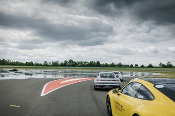 Eine Gruppe vom Porsche Sportwagen wartet darauf, eine Übung auf der bewässern Rennstrecke des Porsche experience in Leipzig zu machen