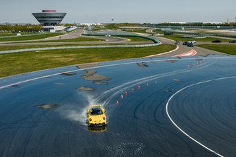 Deine Luftaufnahme zeigt einen gelben Porsche 911 GT3 Er trifft auf der Bewässern Kreisbahn.