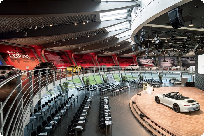 Blick in das Porsche Auditorium, mit Eventbestuhlung und Fahrzeug auf der Bühne