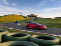 Mehrere Porsche Rennfahrzeuge fahren als Gruppe durch die Kurven der Rundstrecke.