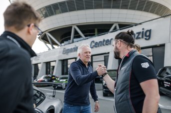 Teilnehmer eines Fahr Events, klatschen mit dem Instrukteur in der Boxengasse des experience Center Leipzig ab