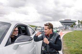 Ein Instrukteur erklärt einem Teilnehmer das richtige Fahrzeughandling auf der Rennstrecke