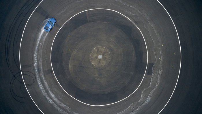 Ein blauer Porsche neun elf bei einer Drift Fahrt auf der Bewässern Kreisbahn des Porsche experience Center, Leipzig