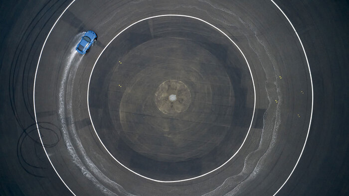 Ein blauer Porsche neun elf bei einer Drift Fahrt auf der Bewässern Kreisbahn des Porsche experience Center, Leipzig