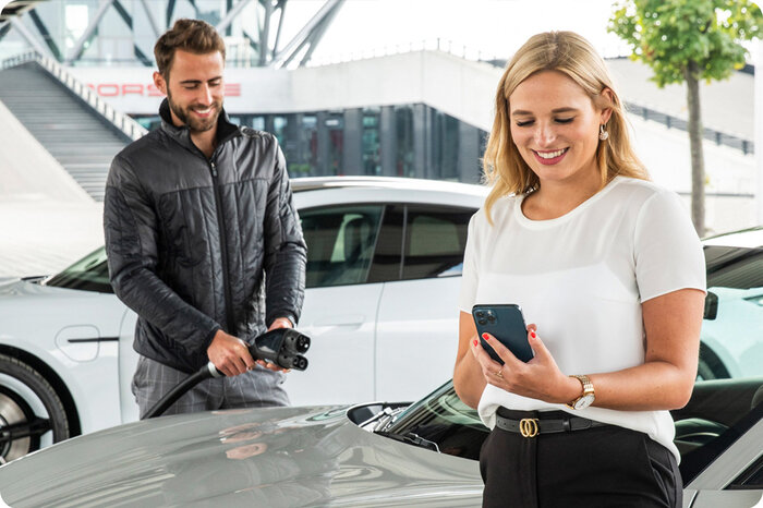 Ein Pärchen lädt ihren Porsche Thycan im Lade Park des Porsche experience Center Leipzig