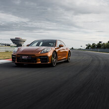 Ein Porsche Panamera auf der Rheinstrecke und im Hintergrund das Porsche experience Center