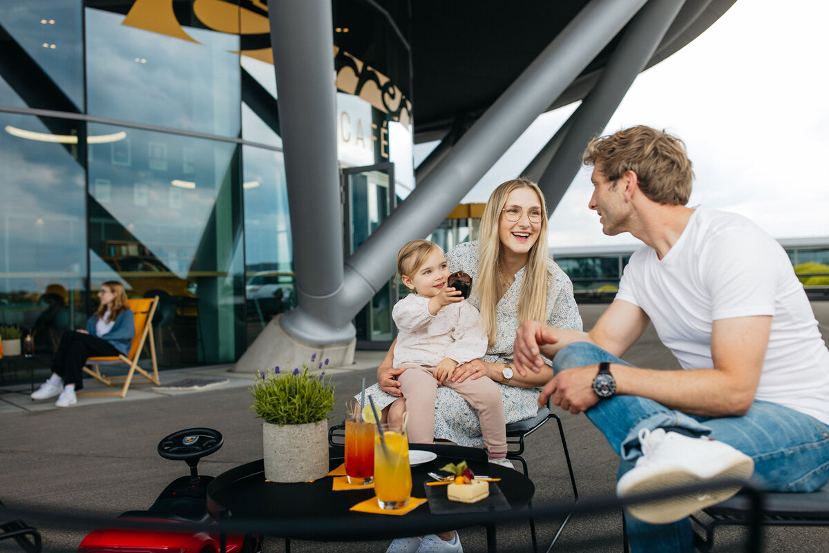 Loungestühle und Tische. Familie mit Kind genießt Getränke.