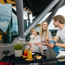 Loungestühle und Tische. Familie mit Kind genießt Getränke.