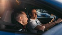 Instrukteur weißt Mann im Fahrzeug ein und erklärt alles rund um das Auto.