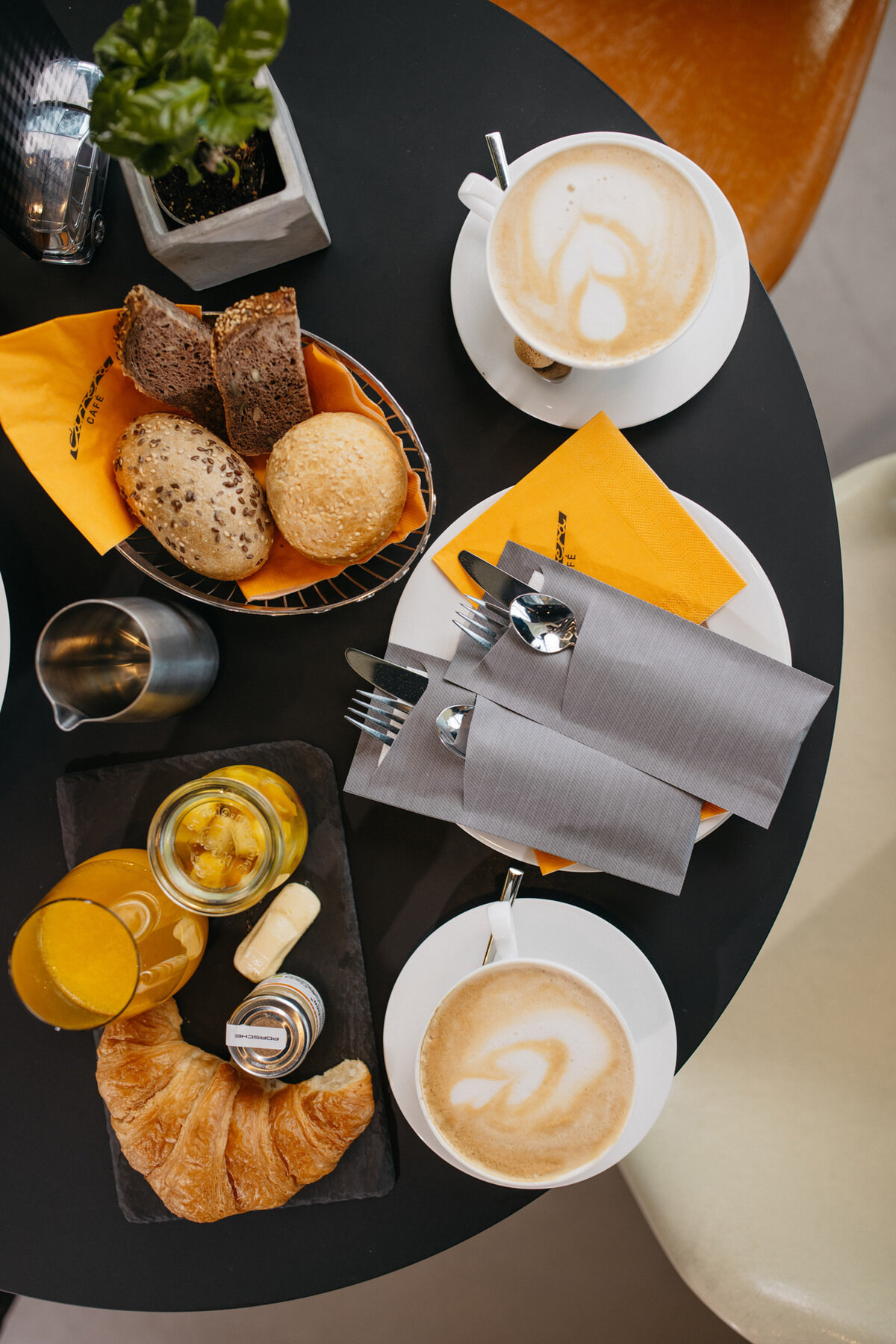 Tisch mit Frühstück. Diverse Brötchen, Croissant, Orangensaft, Cappuchino, Obst.