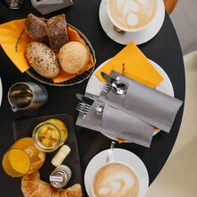 Tisch mit Frühstück. Diverse Brötchen, Croissant, Orangensaft, Cappuchino, Obst.