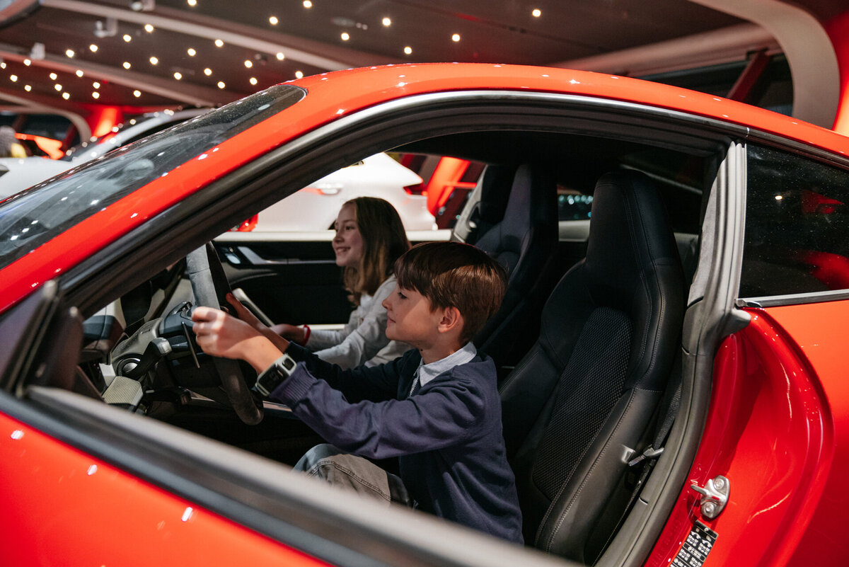 Kinder sitzen in der historischen Fahrzeugausstellung in einem Auto und schauen es sich von innen an.