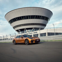 Ein Porsche Panamera auf der Rheinstrecke und im Hintergrund das Porsche experience Center