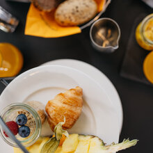 geschnittene Ananas. Müsli mit Heidelbeeren und Himbeeren. Diverse Brötchen und Croissants. 