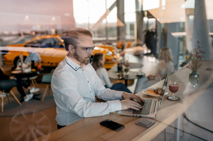 Ein Mann sitzt im Carrera Cafe und arbeitet an seinem Laptop.
