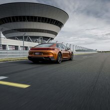Ein Porsche Panamera auf der Rheinstrecke und im Hintergrund das Porsche experience Center