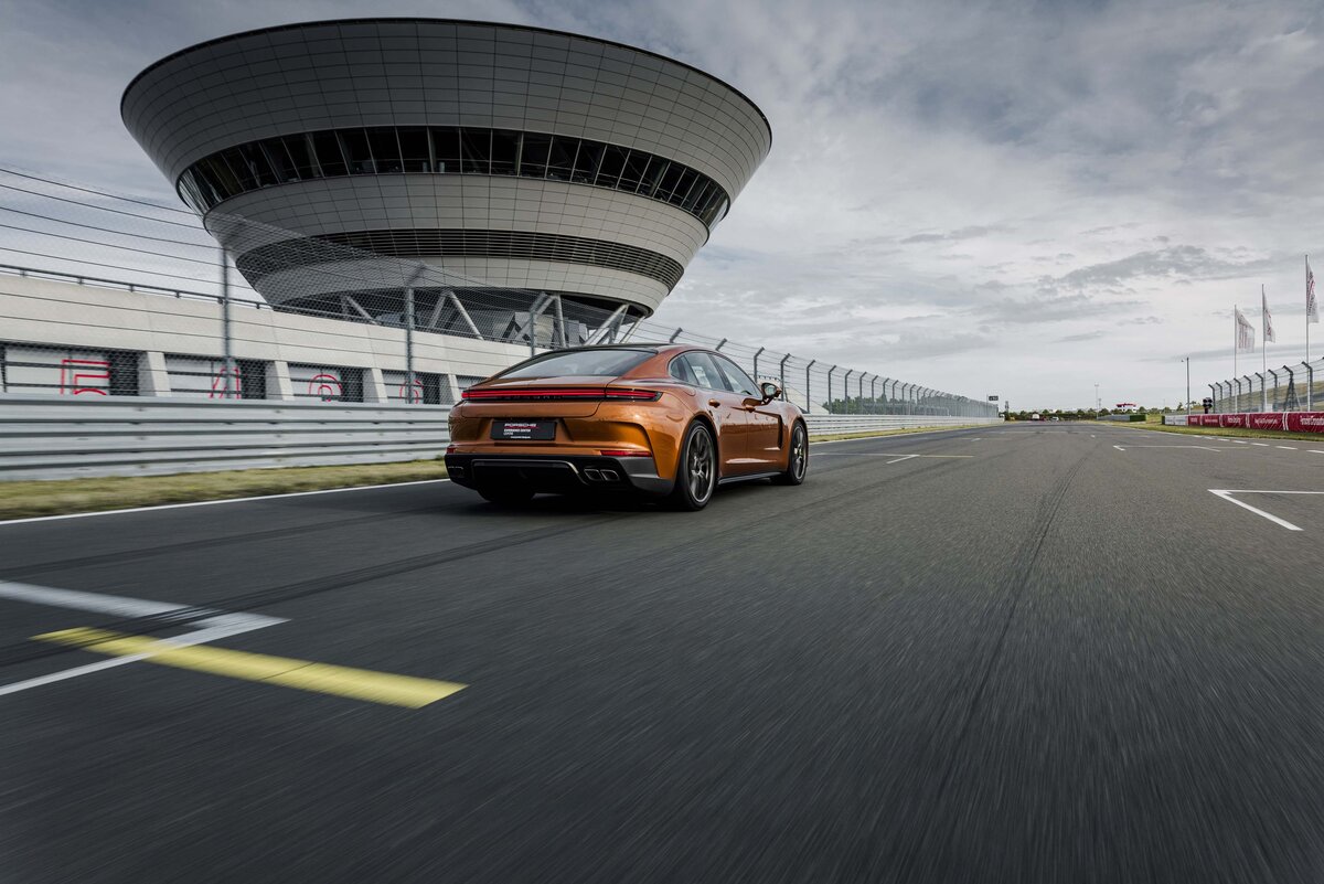 Ein Porsche Panamera auf der Rheinstrecke und im Hintergrund das Porsche experience Center