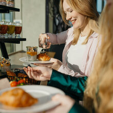 zwei junge Frauen bedienen sich am Buffet. Eine Frau nimmt sich Chia-Pudding.