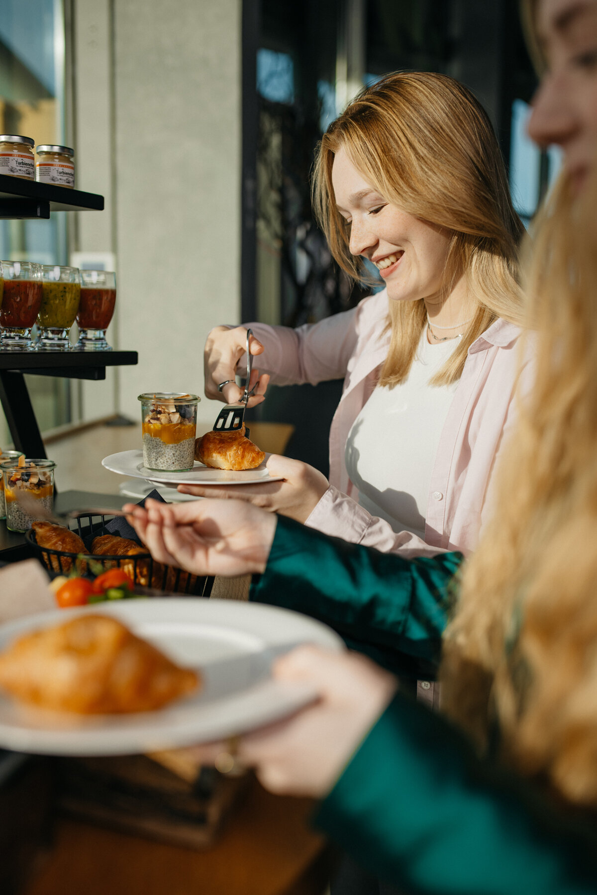 zwei junge Frauen bedienen sich am Buffet. Eine Frau nimmt sich Chia-Pudding.