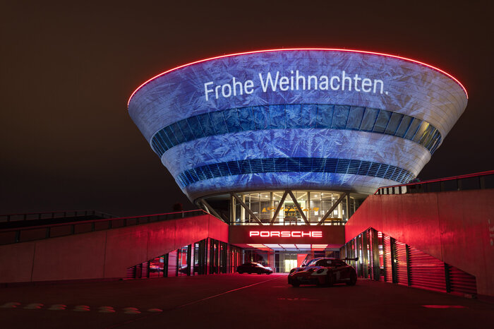 The Experience Center in the dark. It is illuminated with the words “Merry Christmas.”