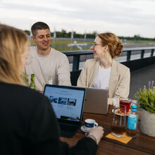 Terrassentische mit Bänken. Mehrere Personen arbeiten an ihren Laptops zusammen.
