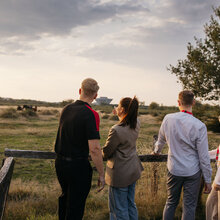 Four people watch the sunset from the terrace of the Off-Road event site.