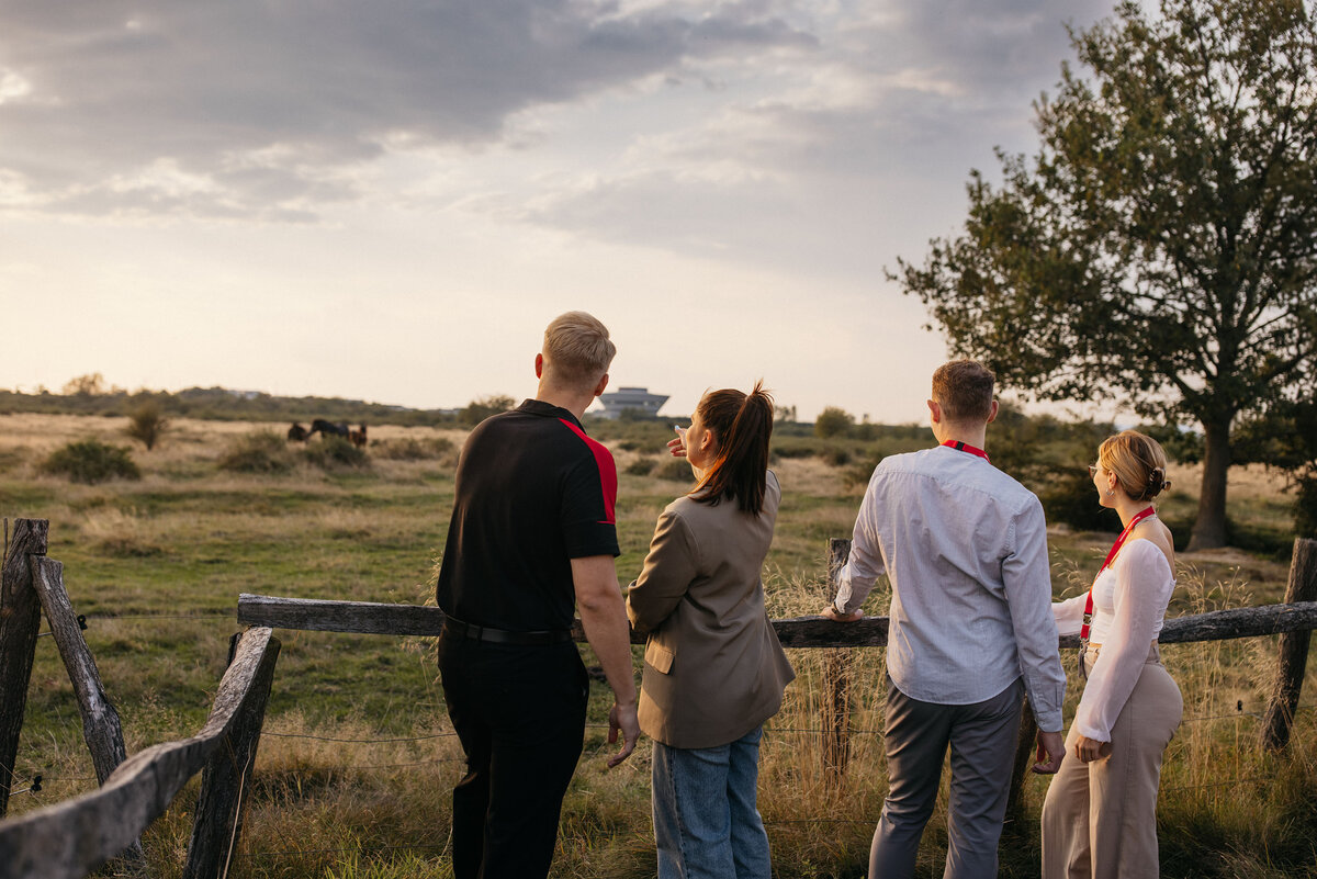Four people watch the sunset from the terrace of the Off-Road event site.