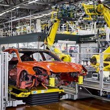Die macan Karosserie mit Unterboden befindet sich im Produktionsschritt bei dem die Fenster verbaut werden. Hier ist das Auto in einer Art Glaskasten und die fenster werden von Robotern verklebt. Sie sehen aus wie lange Arme.