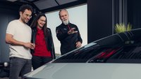Ein Pärchen bekommt von einem Instrukteur ihr neues Fahrzeug erklärt und übergeben