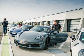 Eine Gruppe von Teilnehmern steigt in ihre Fahrzeuge in der Boxengasse des Porsche Ex experience Center Leipzig ein