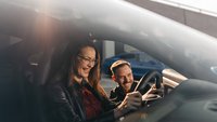 Eine Frau bekommt von einem Instrukteur Details zu ihrem Fahrzeug erklärt