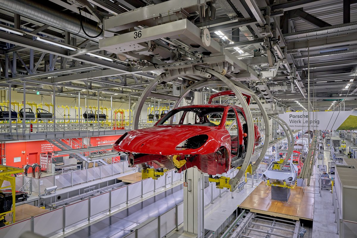 Eine Macan Karosserie hängt an einer speziellen fahrbaren Hängevorrichtung. Die Hängevorrichtung kann sich drehen. Hier wird die Karosserie des Macans vorbereitet, um den Unterbau zu verbauen. Die Karosserie hängt von der Decke. 