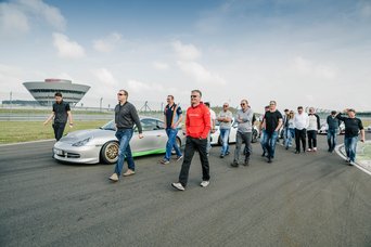 Eine Gruppe von Teilnehmern bei einem Track Walk auf der Rennstrecke des Porsche experience Center Leipzig
