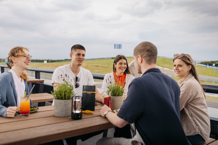 mehrer Personen sitzen auf der Terasse des Carrera Cafes und unterhalten sich.