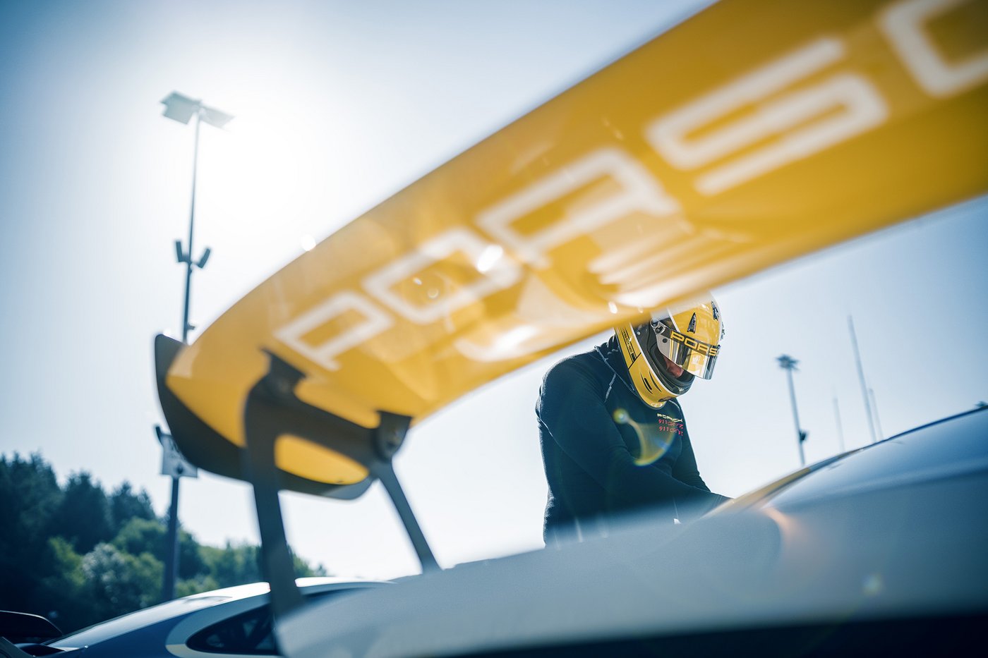 Ein Teilnehmer steht neben einem Porsche Sportwagen